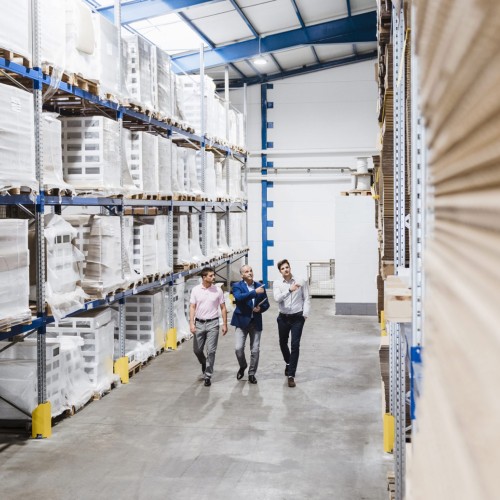 Three people walking through a warehouse